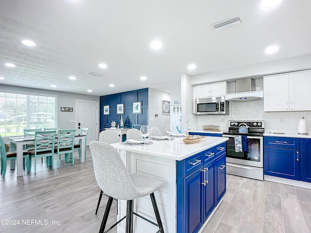 kitchen with appliances with stainless steel finishes, light wood-type flooring, blue cabinets, white cabinets, and a center island