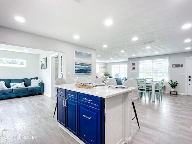 kitchen with light wood-type flooring, a kitchen breakfast bar, a center island, and blue cabinetry