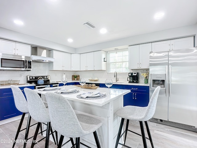 kitchen featuring blue cabinetry, appliances with stainless steel finishes, a center island, and white cabinetry