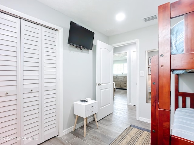 bedroom with light hardwood / wood-style floors and a closet