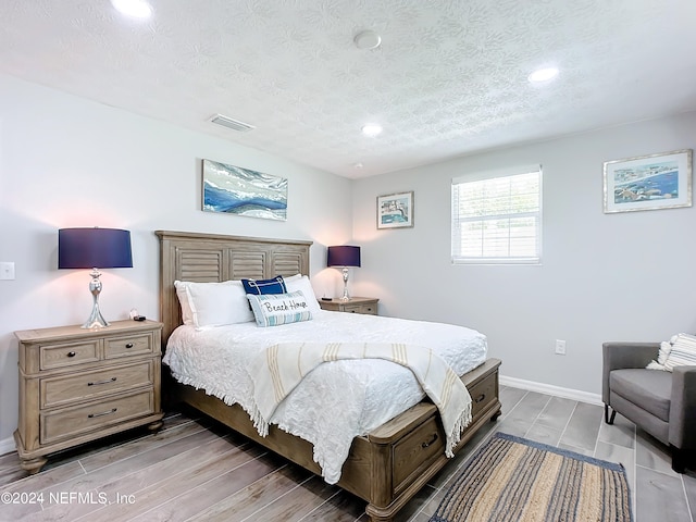 bedroom featuring a textured ceiling and light hardwood / wood-style floors