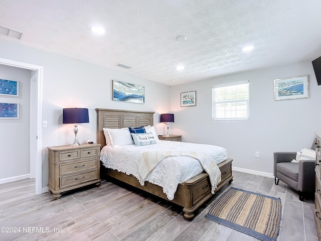 bedroom featuring light hardwood / wood-style flooring and a textured ceiling