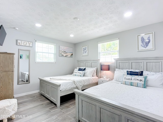 bedroom with light hardwood / wood-style floors and a textured ceiling