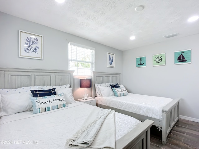 bedroom with dark hardwood / wood-style flooring and a textured ceiling