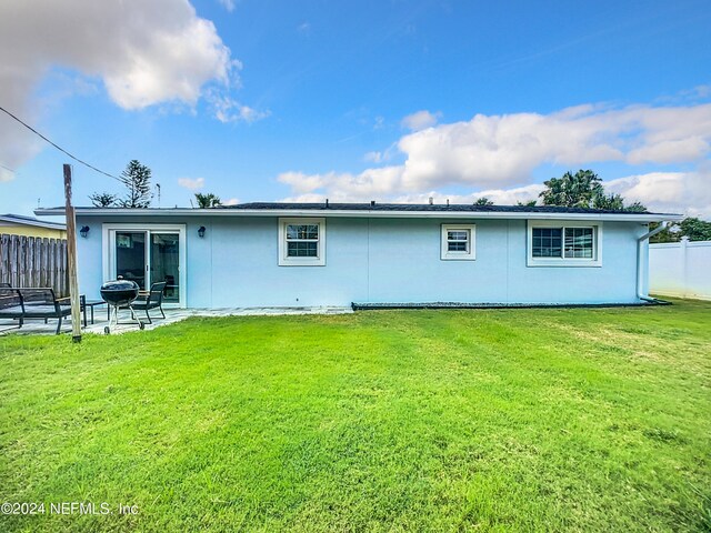 back of property with a yard and a patio