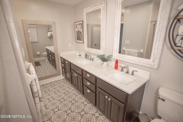 bathroom featuring toilet, double vanity, a sink, and tile patterned floors