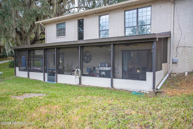 view of front of property with a front yard, a sunroom, and brick siding