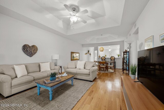 living room featuring a tray ceiling, hardwood / wood-style flooring, and ceiling fan