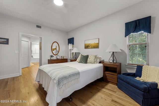 bedroom with ceiling fan, ensuite bath, and hardwood / wood-style floors