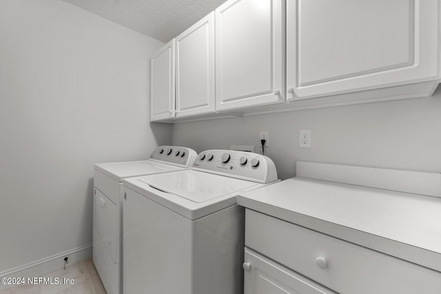 laundry room with washer and dryer, cabinets, a textured ceiling, and light tile floors