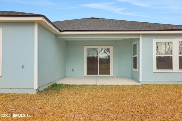 back of property with a patio area, stucco siding, a lawn, and roof with shingles