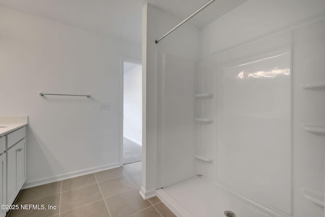 bathroom featuring tile patterned flooring, vanity, and a shower