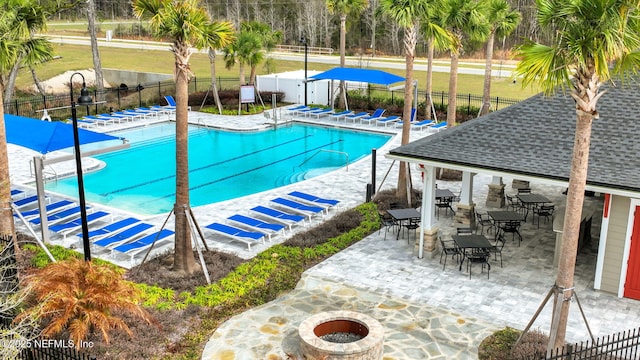 community pool featuring a patio area, an outdoor fire pit, and a fenced backyard