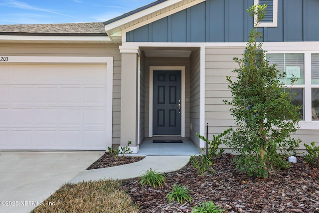 doorway to property with board and batten siding, an attached garage, and roof with shingles