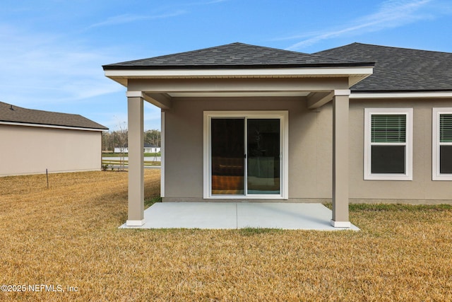 back of house featuring a patio, stucco siding, a lawn, and a shingled roof