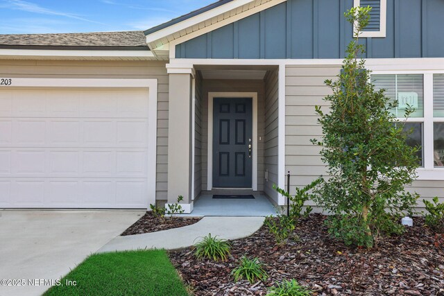 property entrance featuring board and batten siding, an attached garage, and roof with shingles