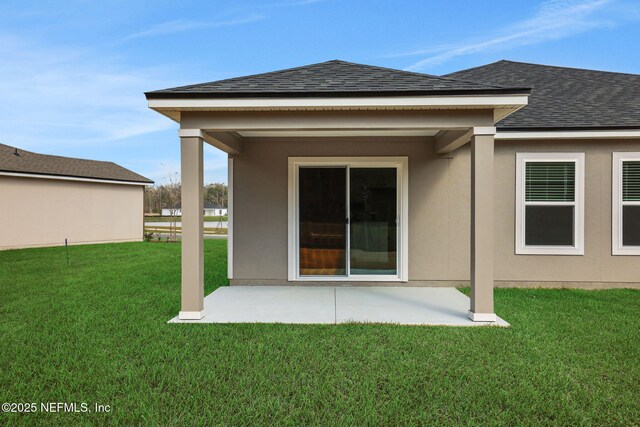 rear view of property with a yard, a patio area, stucco siding, and a shingled roof