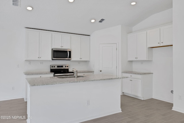 kitchen with visible vents, wood tiled floor, a sink, stainless steel appliances, and white cabinetry