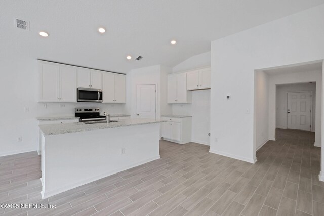 kitchen featuring a center island with sink, visible vents, a sink, appliances with stainless steel finishes, and white cabinetry