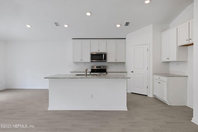 kitchen featuring white cabinets, light stone counters, visible vents, and appliances with stainless steel finishes