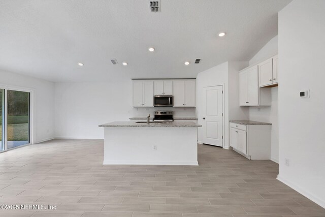 kitchen featuring white cabinetry, light stone countertops, a kitchen island with sink, and stainless steel appliances