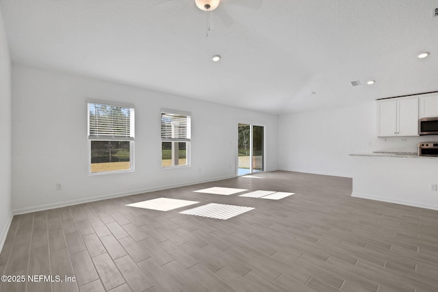 unfurnished living room with a wealth of natural light, baseboards, and light wood finished floors