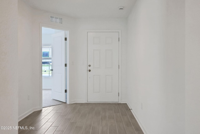 hall featuring visible vents, baseboards, and wood tiled floor