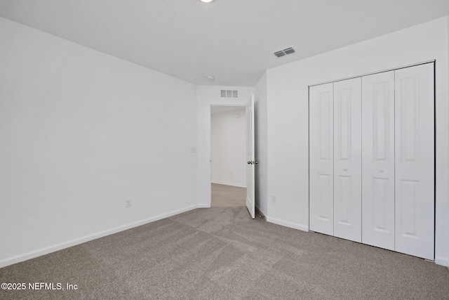 unfurnished bedroom featuring carpet flooring, baseboards, visible vents, and a closet