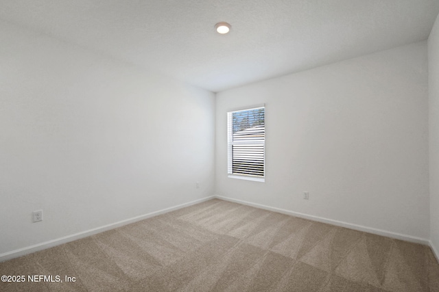 empty room with baseboards and light colored carpet