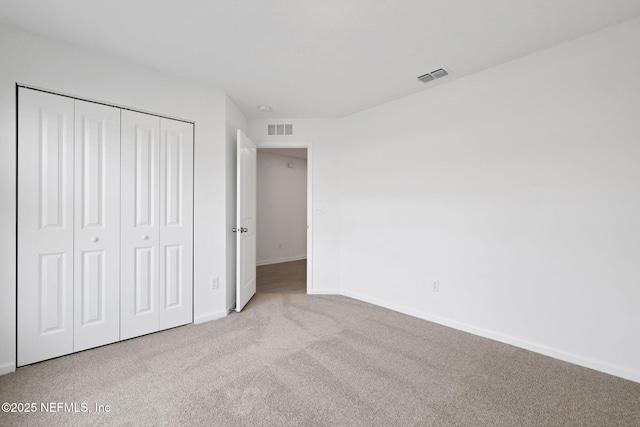 unfurnished bedroom with baseboards, visible vents, carpet floors, and a closet