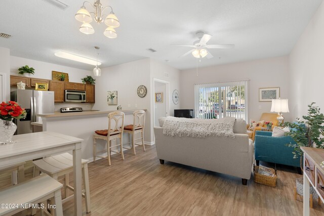 living room featuring light wood-type flooring and ceiling fan with notable chandelier