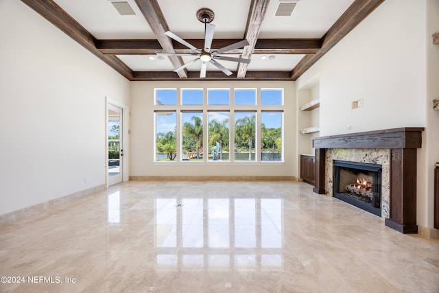 unfurnished living room featuring ceiling fan, beam ceiling, a premium fireplace, coffered ceiling, and built in shelves