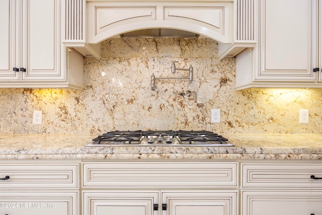 kitchen featuring stainless steel gas cooktop, tasteful backsplash, and light stone countertops