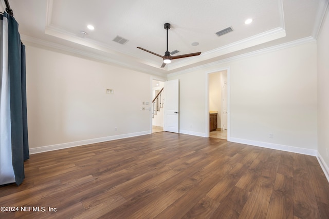 interior space with ceiling fan, a tray ceiling, dark hardwood / wood-style flooring, and crown molding