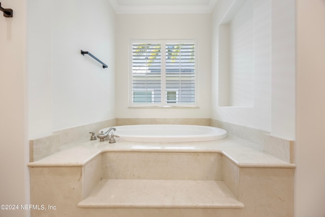 bathroom with ornamental molding and tiled tub