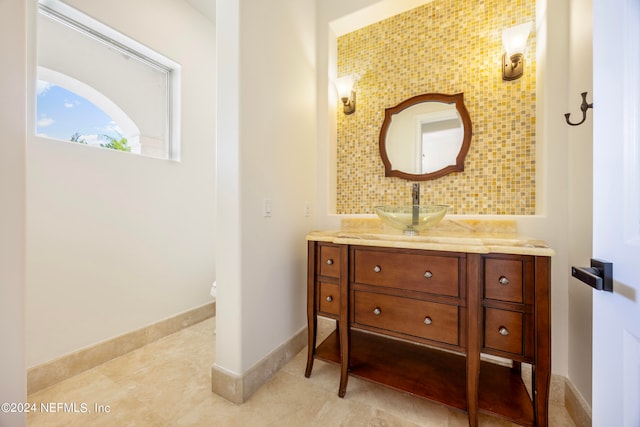 bathroom with toilet, decorative backsplash, and vanity