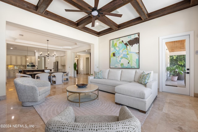 living room featuring ceiling fan with notable chandelier, ornamental molding, beamed ceiling, and coffered ceiling