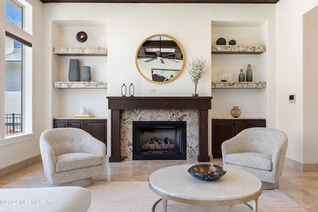 sitting room featuring a premium fireplace, a healthy amount of sunlight, and built in shelves