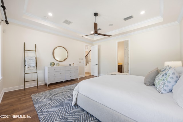 bedroom with ceiling fan, ensuite bathroom, a raised ceiling, and dark hardwood / wood-style flooring