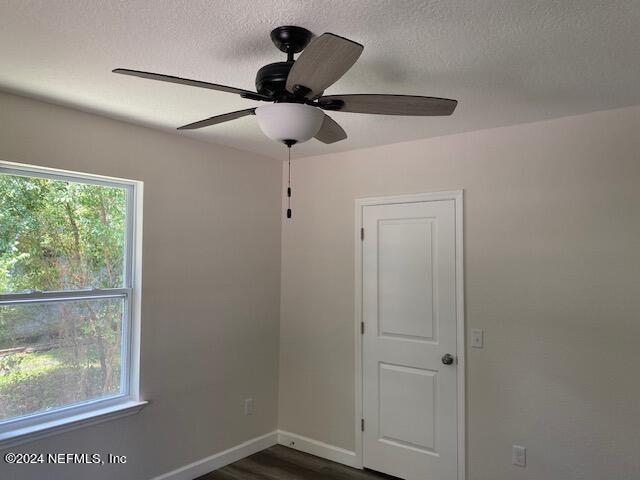 spare room with dark hardwood / wood-style flooring, ceiling fan, and a textured ceiling