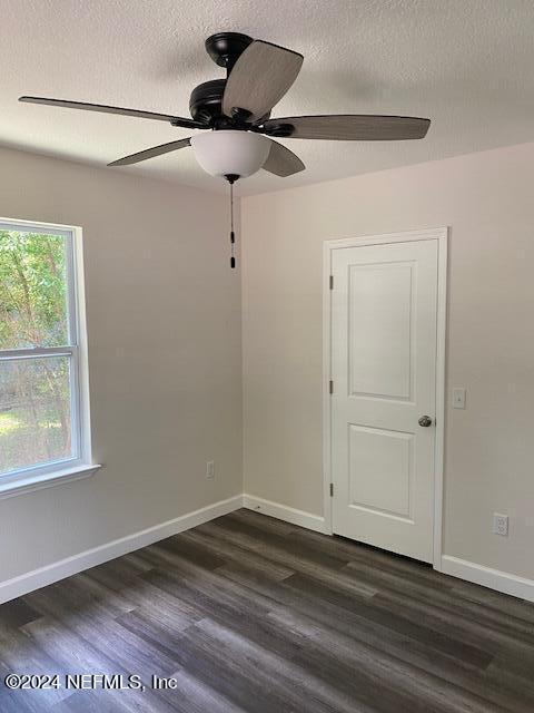 spare room with ceiling fan, dark hardwood / wood-style floors, and a textured ceiling