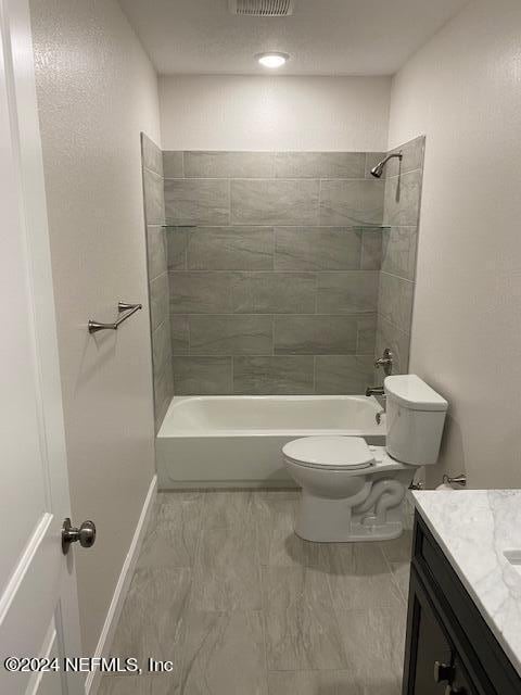 full bathroom with tiled shower / bath, vanity, and toilet