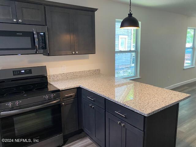 kitchen featuring light hardwood / wood-style floors, light stone countertops, kitchen peninsula, and appliances with stainless steel finishes