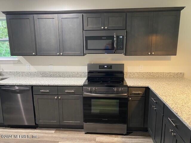 kitchen featuring stainless steel appliances, light stone countertops, and light hardwood / wood-style flooring