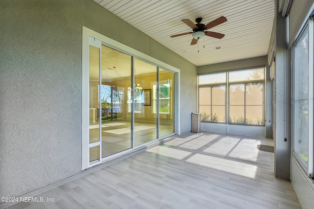 unfurnished sunroom featuring ceiling fan, a healthy amount of sunlight, and wooden ceiling