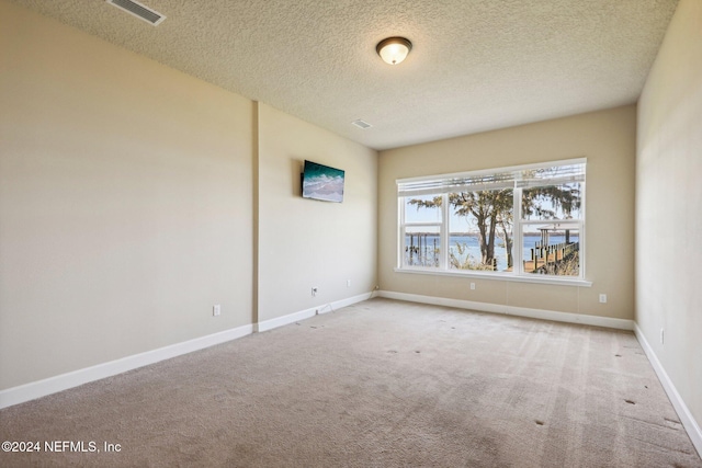 carpeted empty room featuring a textured ceiling