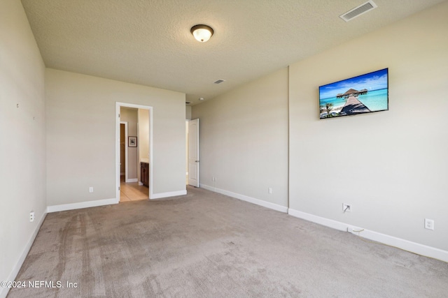 unfurnished bedroom featuring light carpet, a textured ceiling, and connected bathroom