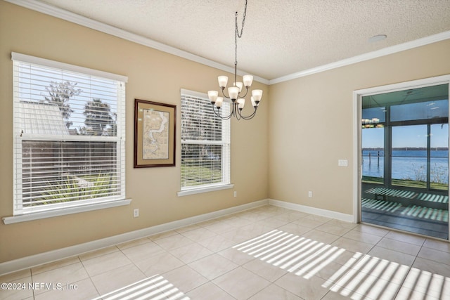 tiled spare room with plenty of natural light, a water view, a textured ceiling, and an inviting chandelier