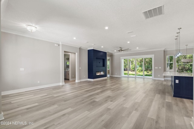 unfurnished living room featuring crown molding, a fireplace, ceiling fan, and light hardwood / wood-style flooring