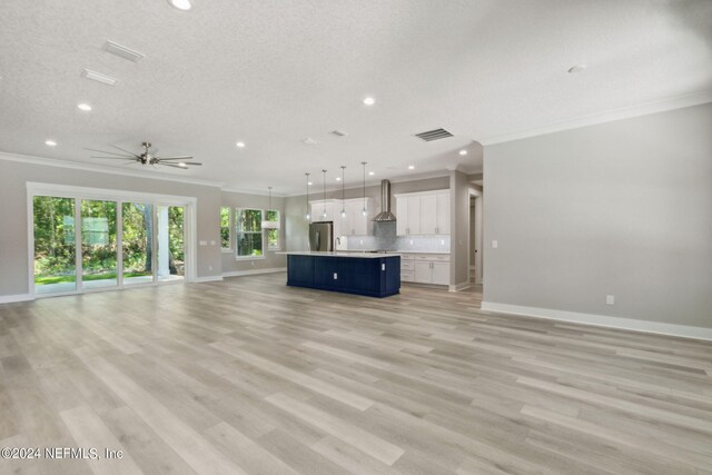 unfurnished living room with ceiling fan, ornamental molding, light hardwood / wood-style flooring, and a textured ceiling